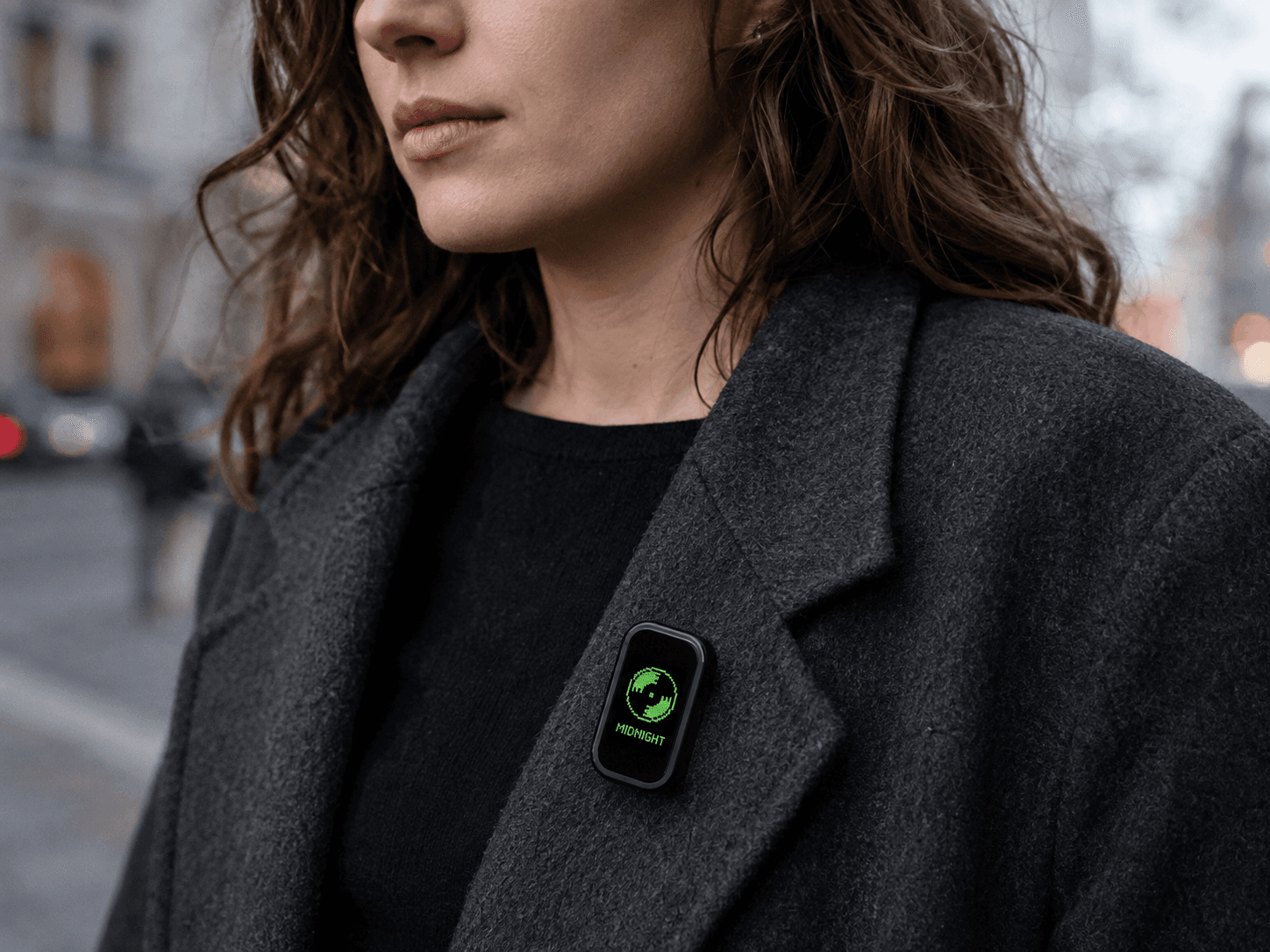 MoodPin on the lapel of a charcoal wool coat, showing a green pixel record and the track MIDNIGHT